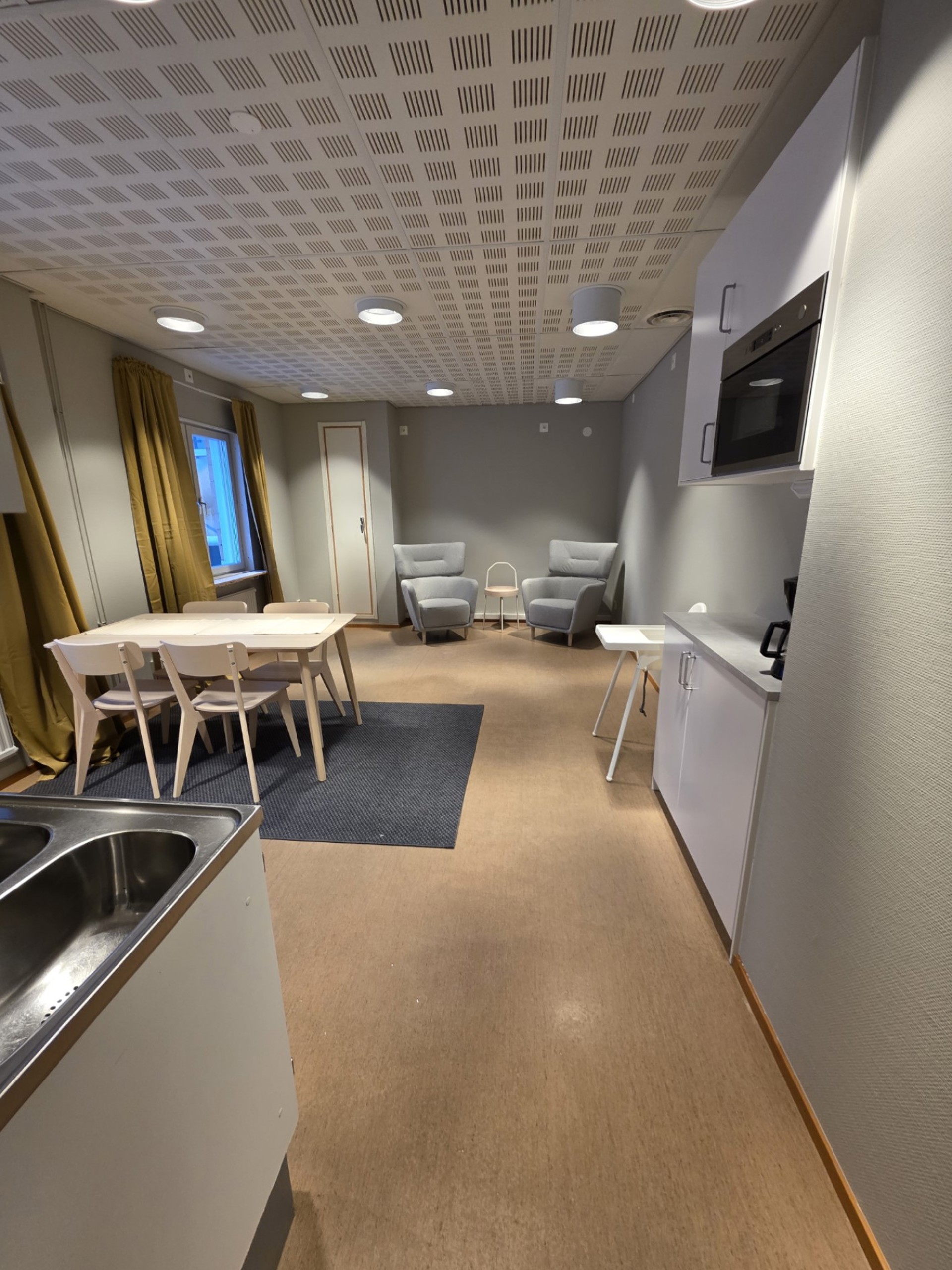 Vardagsrum med köksbord och stolar samt två fåtöljer.