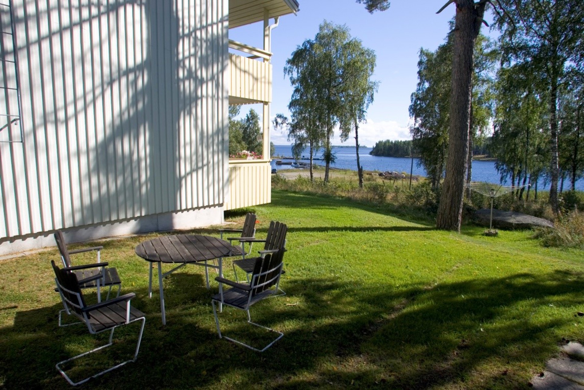 Del av husgavel, stolar och bord i förgrund